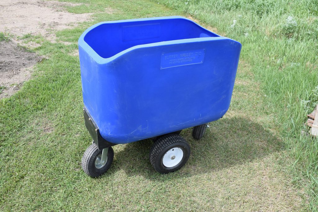 12 bushel plastic feed cart sitting on grass